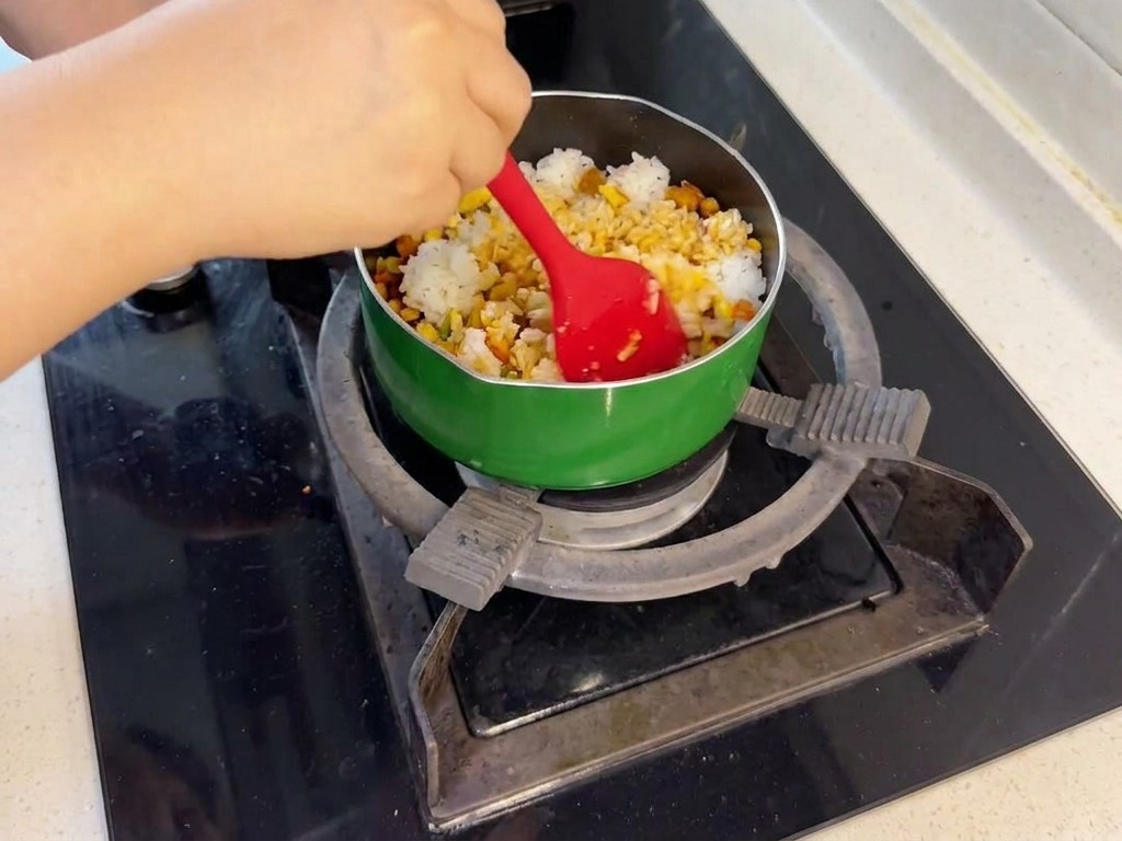 Una persona usando una espátula roja para combinar el arroz blanco con el salmón y las verduras en la sartén.
