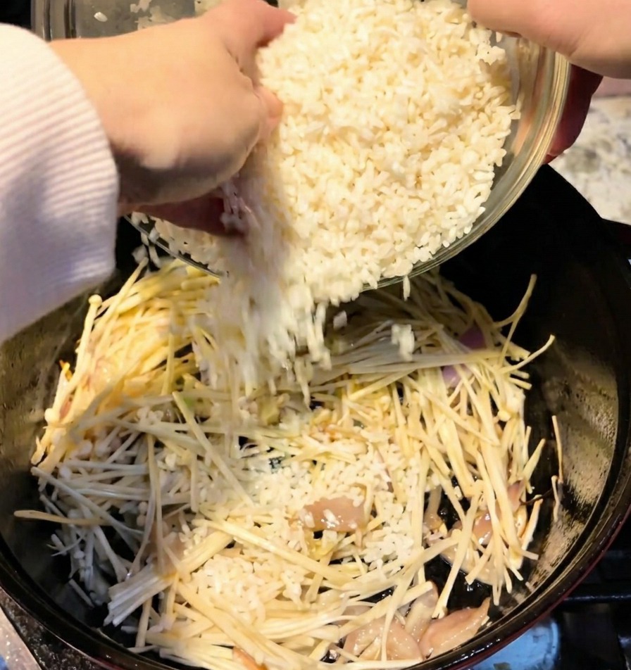 Dos tazas de arroz blanco vertiéndose desde un cuenco a una olla que contiene setas.