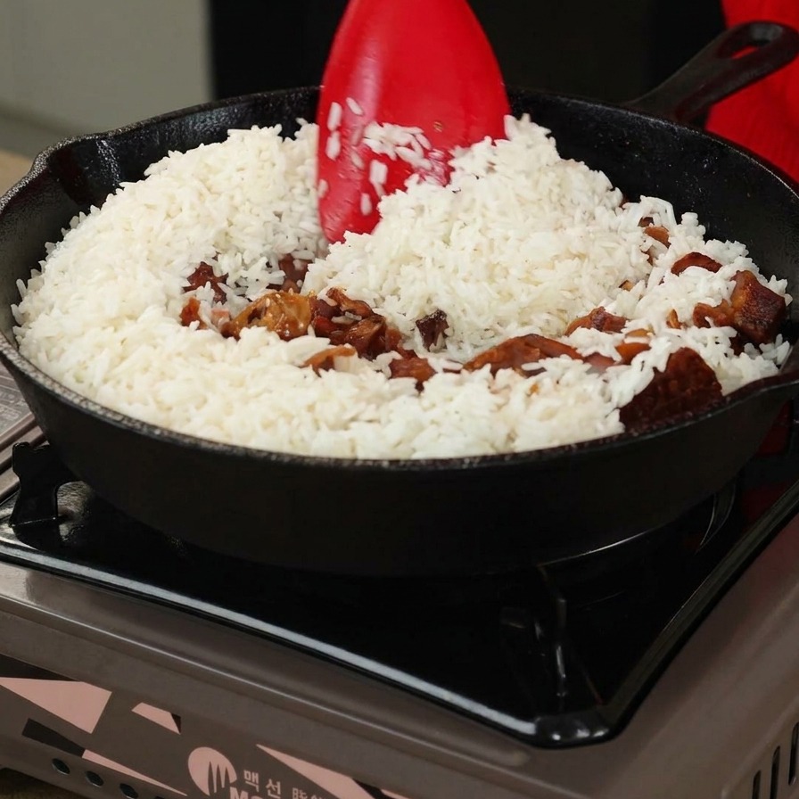 Arroz y setas siendo removidos con una espátula roja en una sartén de hierro.