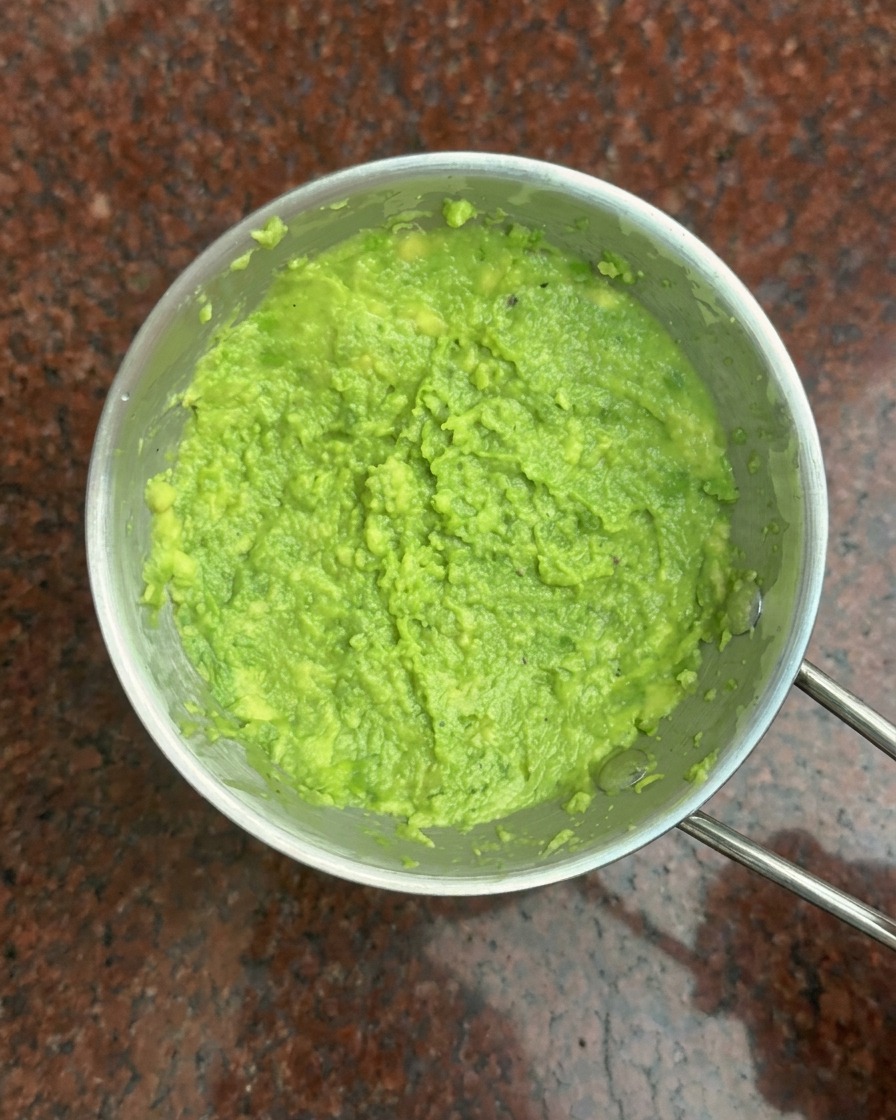 Vista aérea de un bol metálico lleno de puré de aguacate verde vibrante.
