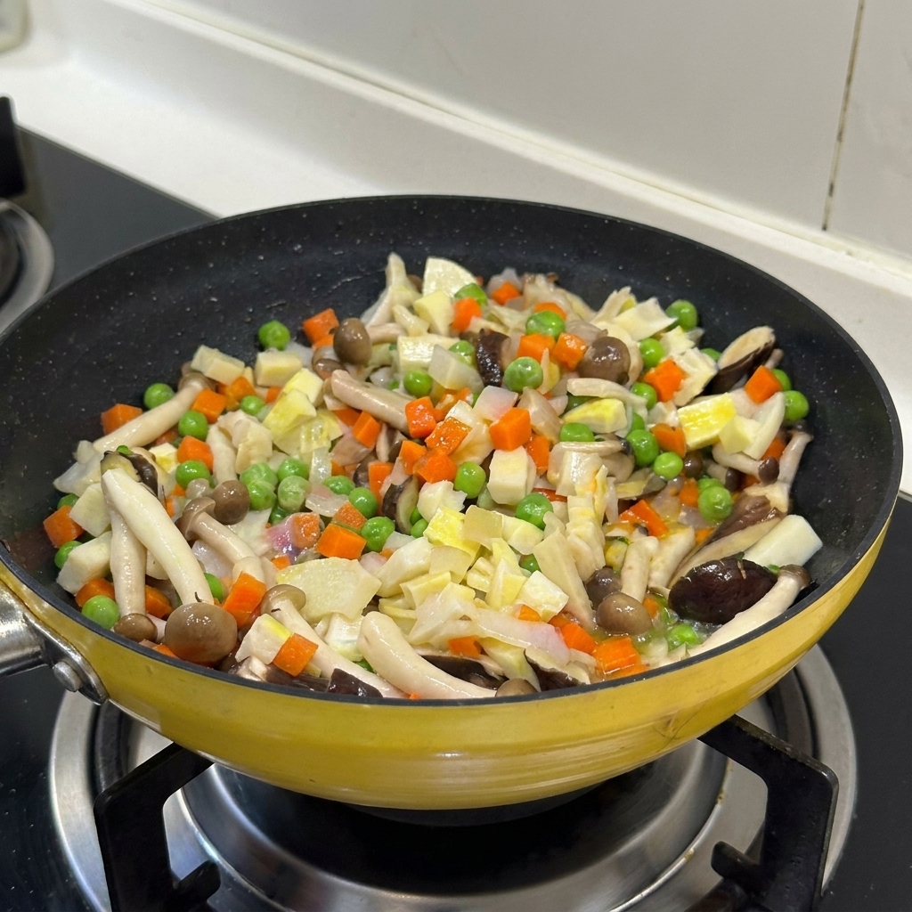 Una mezcla colorida de verduras picadas y setas salteándose juntas en una sartén amarilla.