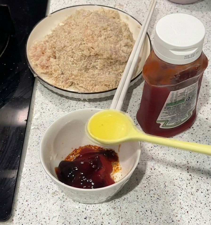 Una cuchara vertiendo aceite caliente en un cuenco blanco con kétchup y especias.