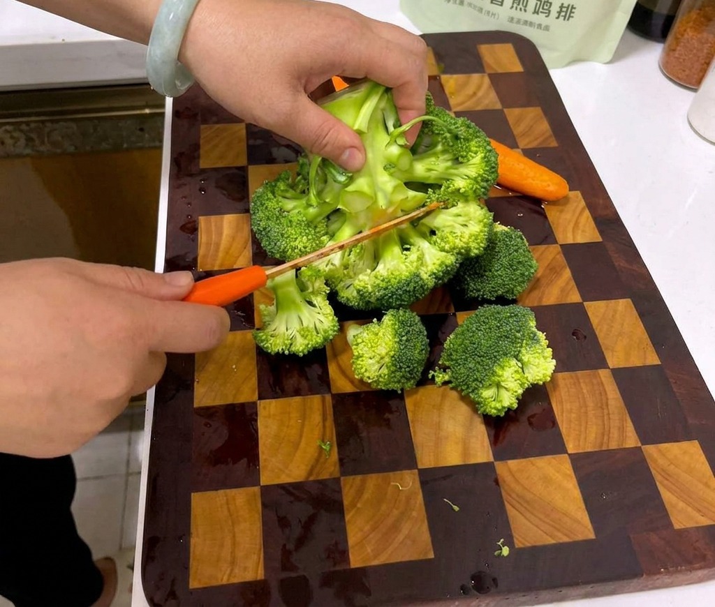 Manos cortando una cabeza grande de brócoli en pequeños floretes sobre una tabla de cortar de madera.