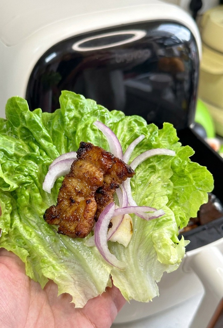 Una hoja de lechuga con ajo, cebolla y un trozo de panceta asada brillante y dorada.