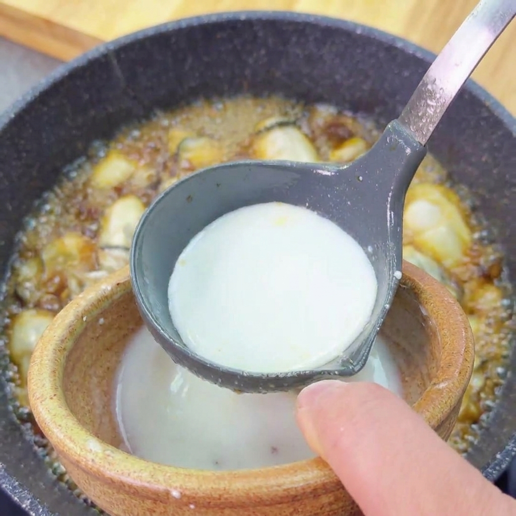 Una mezcla blanca de fécula de patata vertiéndose desde un bol pequeño en un cucharón gris sobre el plato de ostras.