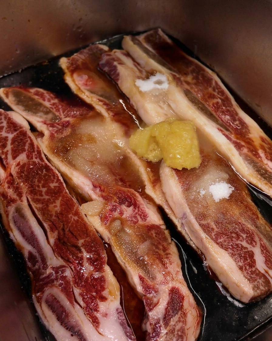 Primer plano de un montón de ajo picado sobre costillas de ternera veteadas en marinada de soja.