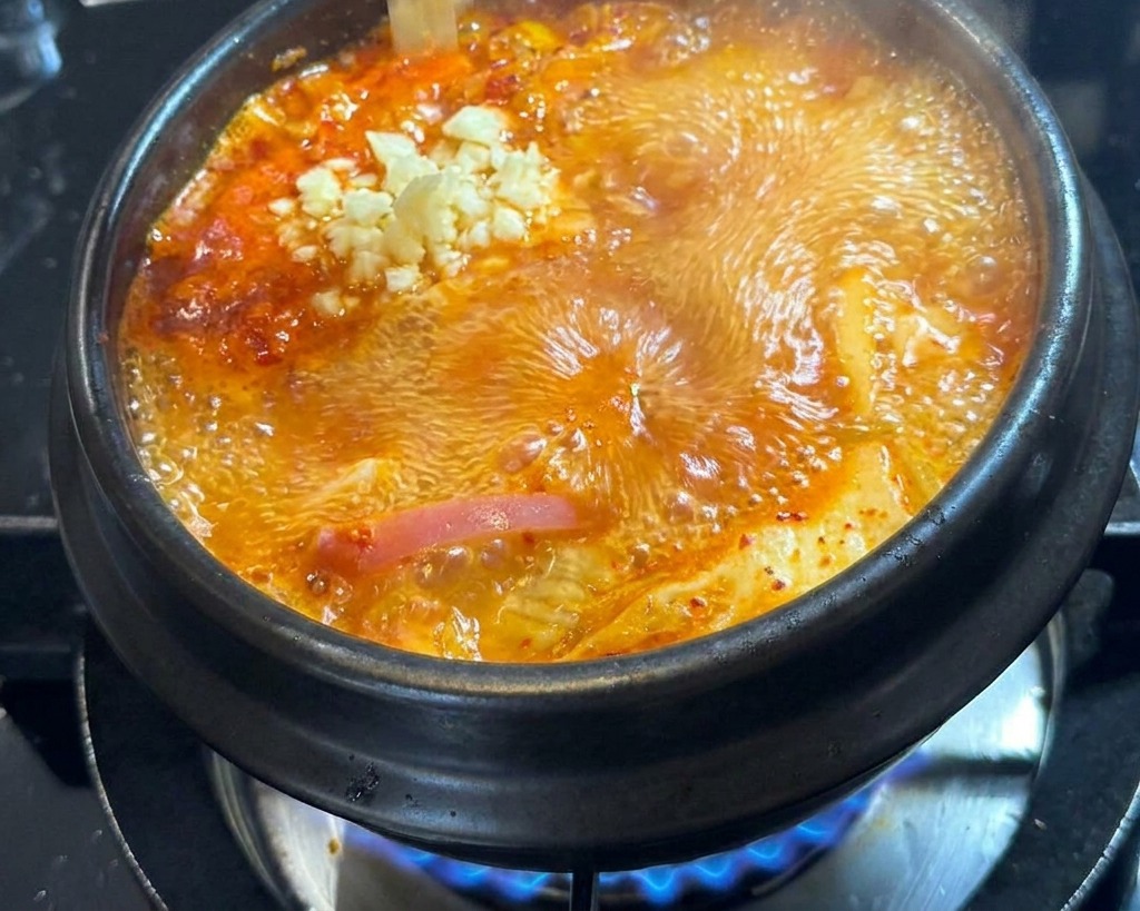 Ajo picado fresco cayendo en el centro de la cazuela de estofado rojo.