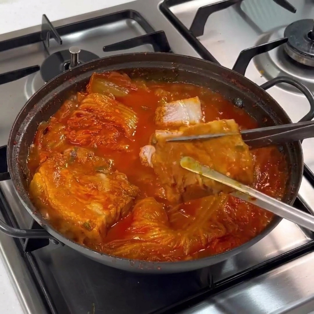 Pinzas sujetando un trozo de panceta cocida mientras unas tijeras lo cortan en rodajas dentro del estofado.
