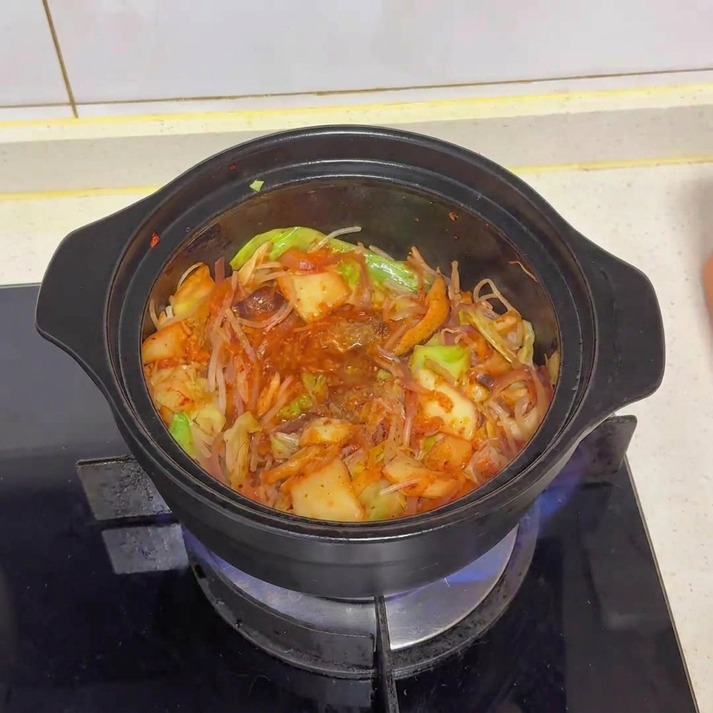 Mezcla de vegetales y kimchi en la olla tras añadir el polvo de carne y MSG, mostrando cómo se integran los condimentos.