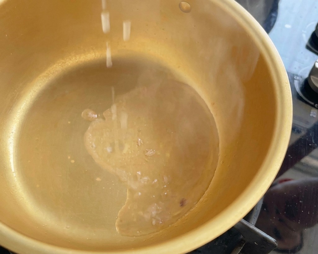 Trozos de cebolleta picada cayendo en una olla humeante con aceite de atún caliente.