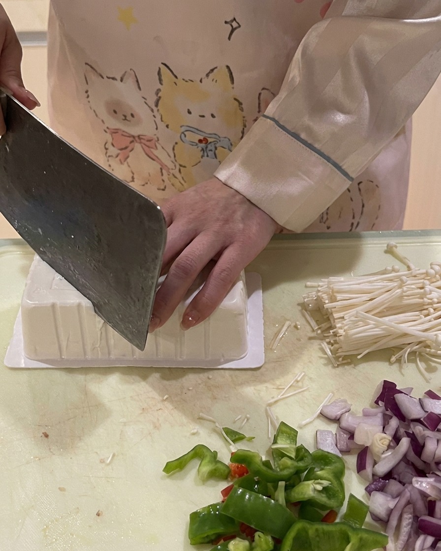Un cuchillo cortando la esquina de una caja de tofu invertida para dejar entrar aire y sacarlo fácilmente.