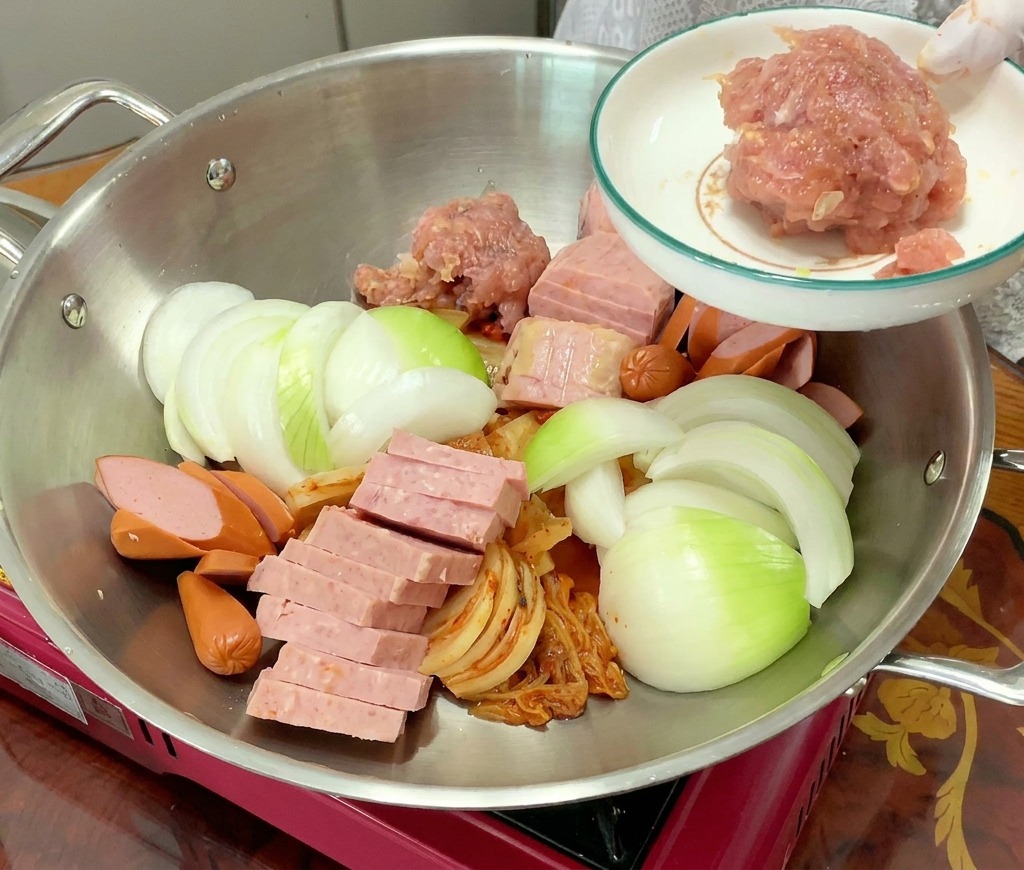 Una porción de carne de cerdo picada sazonada se añade a la olla junto al resto de ingredientes organizados.