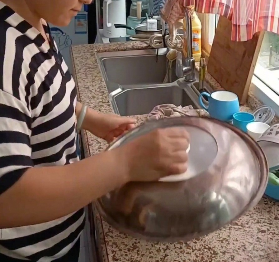 Una persona colocando una tapa de metal sobre un bol con masa para dejarla reposar.