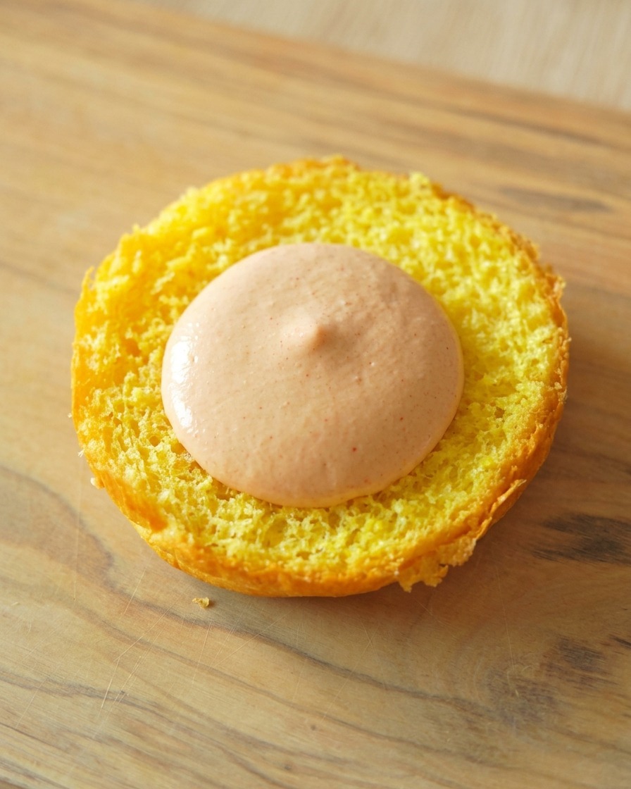 La base tostada de un pan brioche con una generosa porción de salsa naranja en el centro.