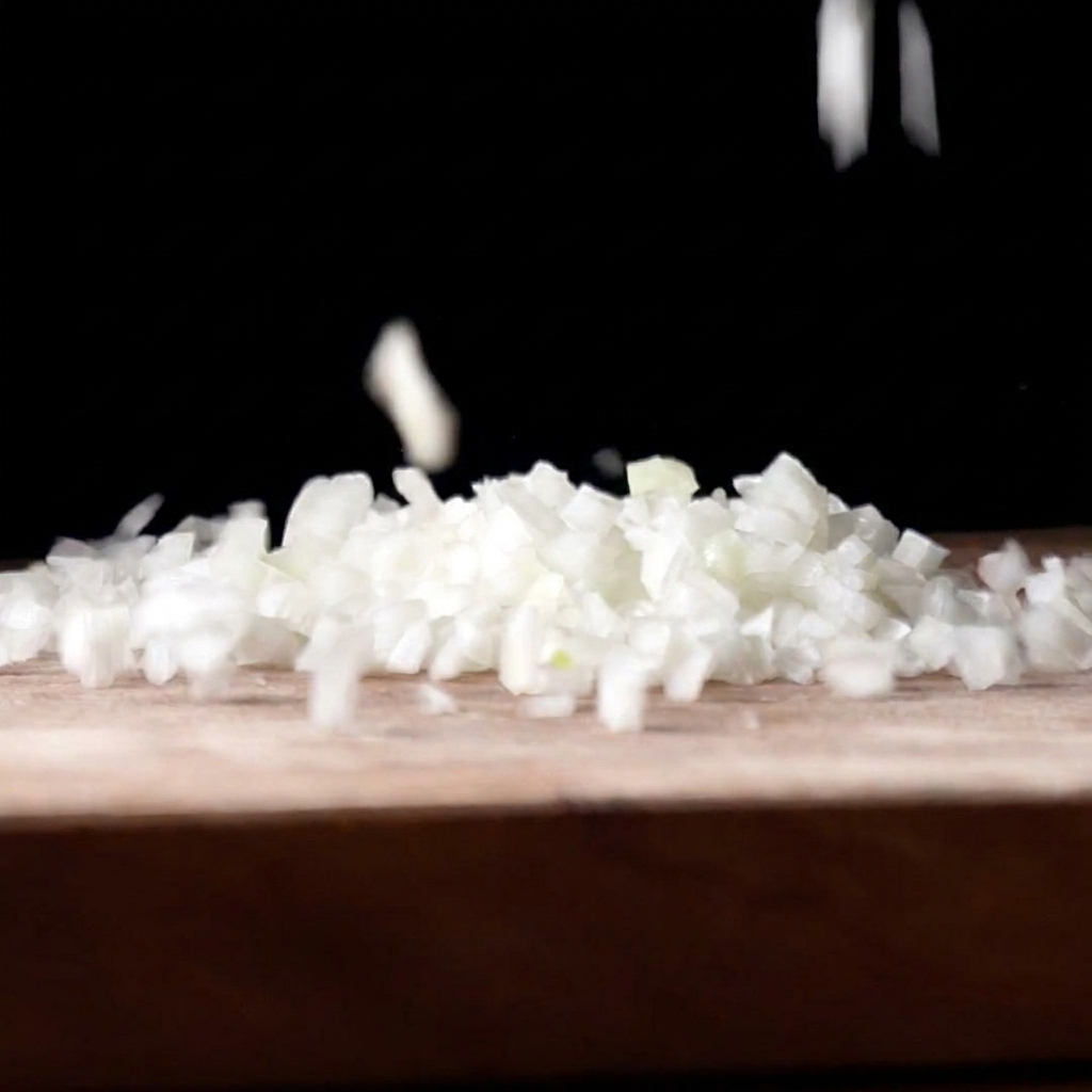 Trozos de cebolla blanca finamente picada cayendo sobre una tabla de cortar de madera sobre un fondo oscuro.