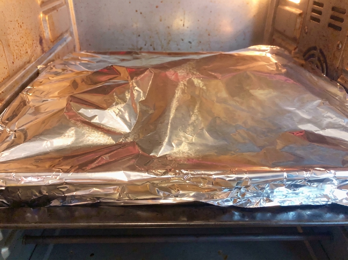 Un molde para hornear cubierto con papel aluminio dentro de un horno casero calentado para hornear.