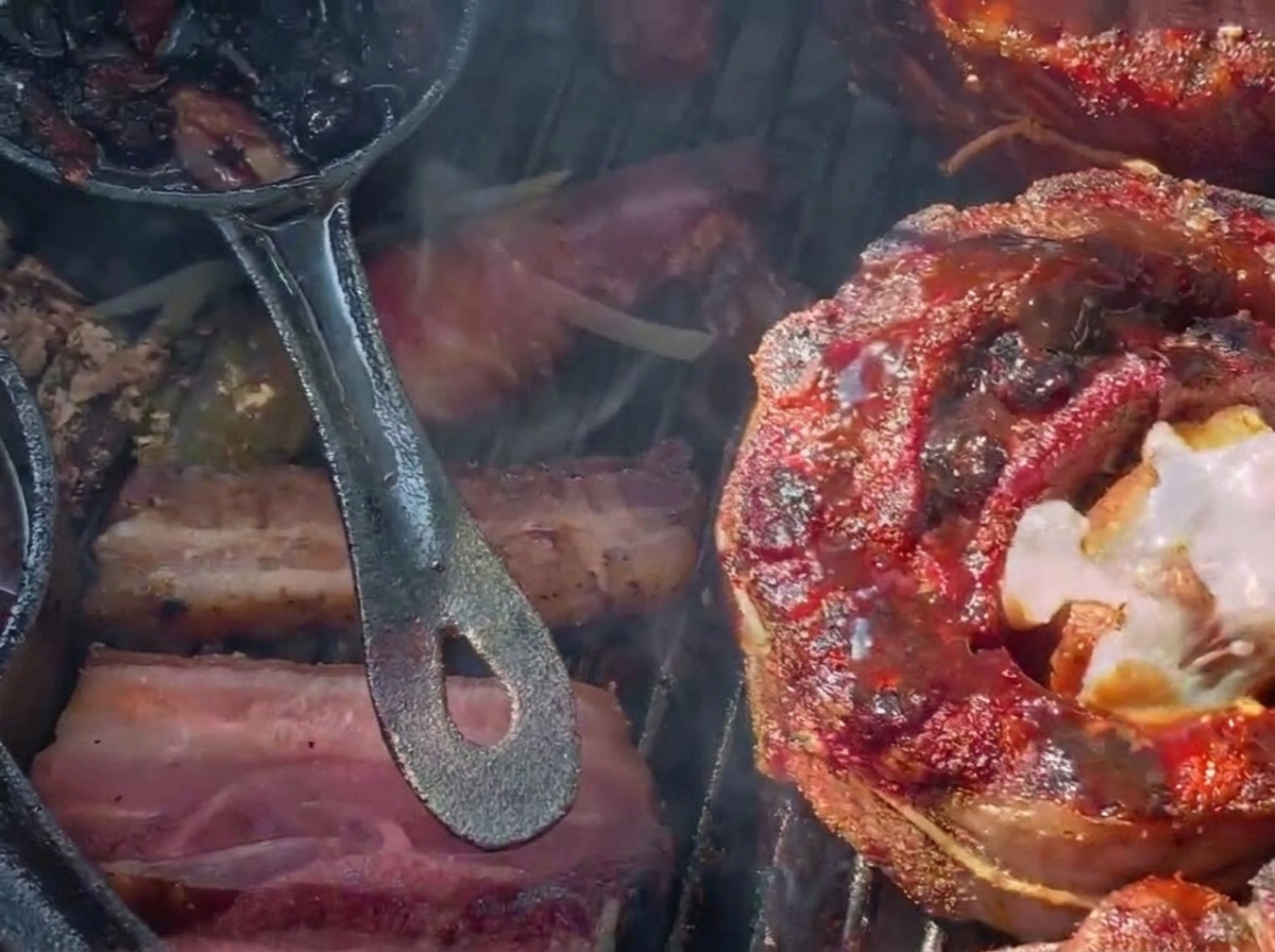 Queso rallado derritiéndose sobre una copa de costilla rellena y oscura con glaseado de arándanos en una parrilla de carbón.