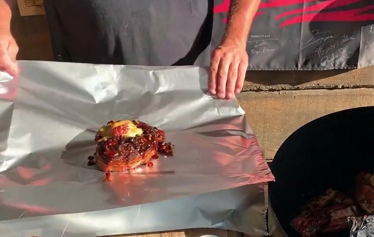 Una copa de costilla St. Louis completamente rellena con queso y salsa, asentada sobre una lámina de papel de aluminio lista para ser envuelta.