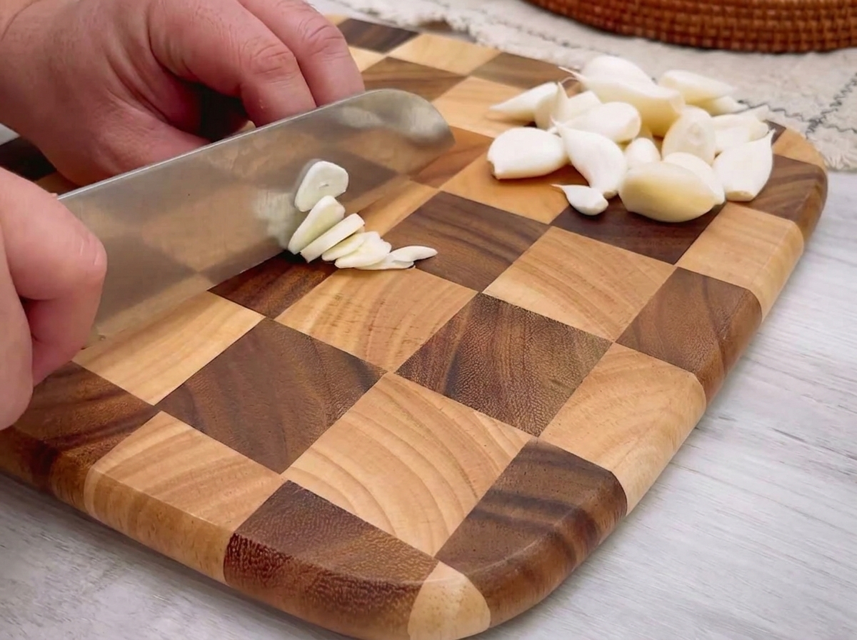 Ajo finamente picado esparcido sobre una tabla de cortar de madera.
