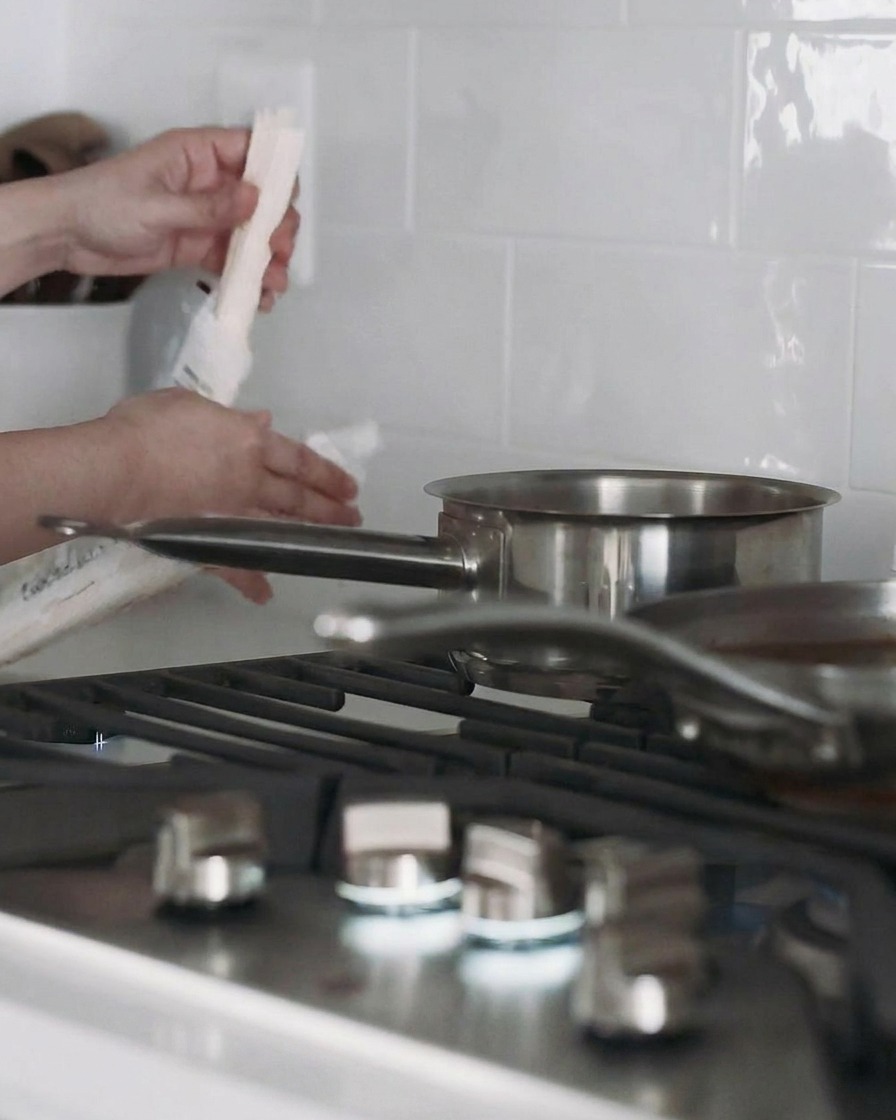 Una olla con agua en la estufa y fideos udon cocinándose dentro.