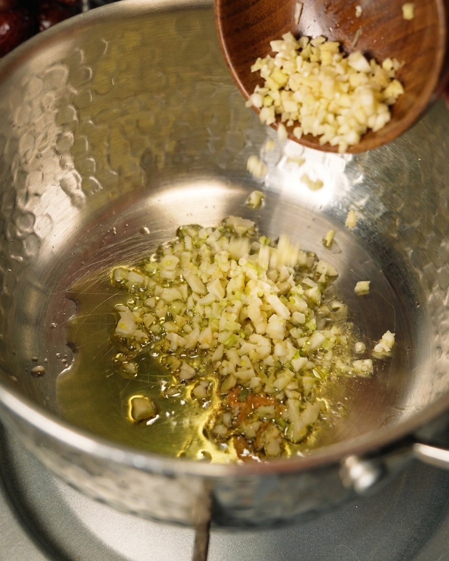 Cebolla y ajo sofriéndose en aceite de oliva dentro de una olla.
