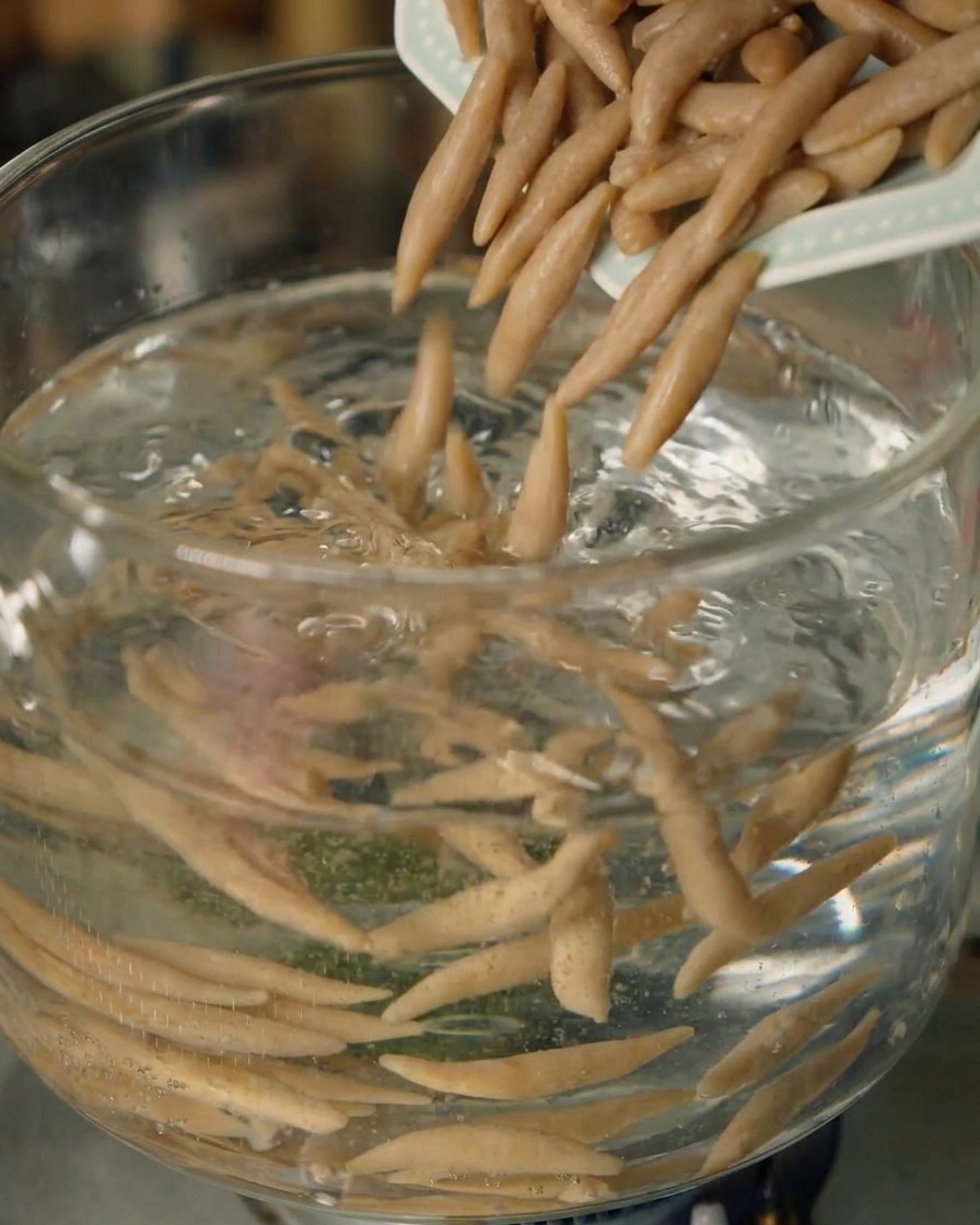 Fideos de avena tipo pez de Shanxi introduciéndose en una olla con agua hirviendo.