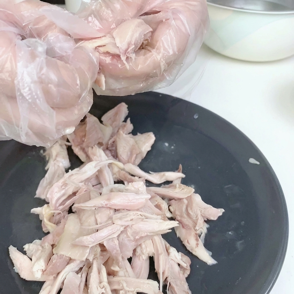 Carne de pollo desmenuzada en un plato blanco, sin piel.