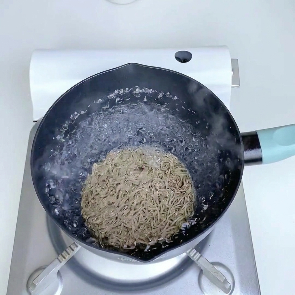 Fideos de trigo sarraceno cocinándose en una olla con agua hirviendo.