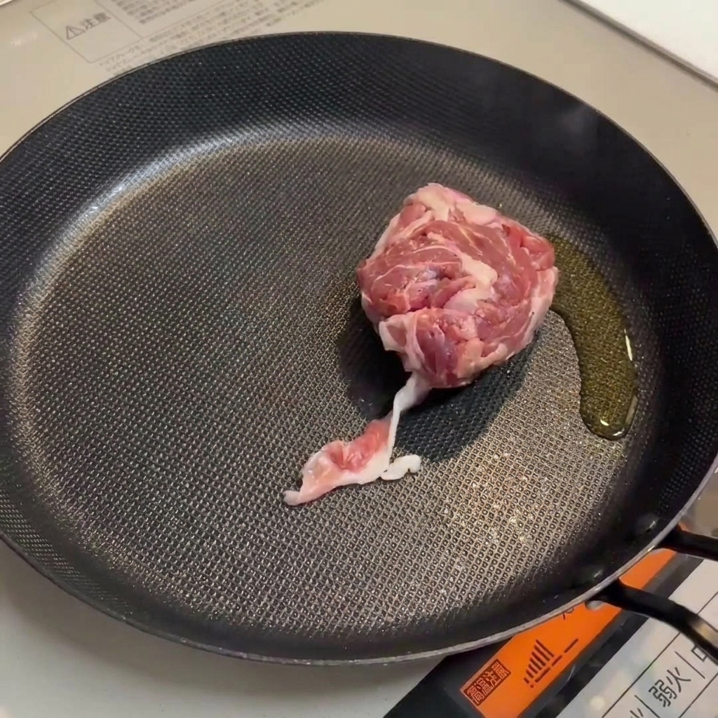 Cerdo y salchichas dorándose en una sartén.