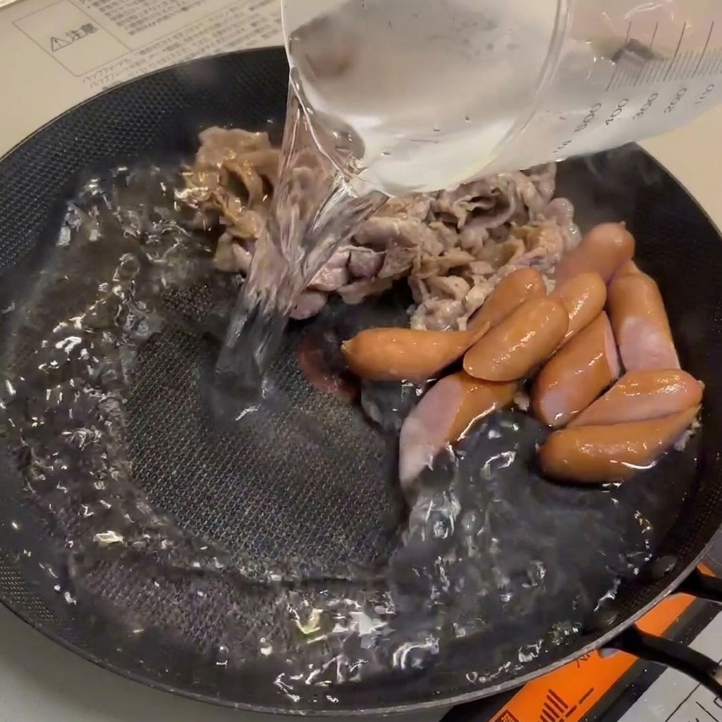 Agua vertiéndose en la sartén sobre la carne.
