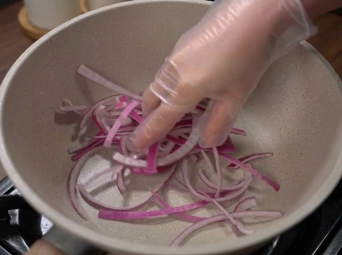 Cebollas y col dispuestas en el fondo de una olla vacía.