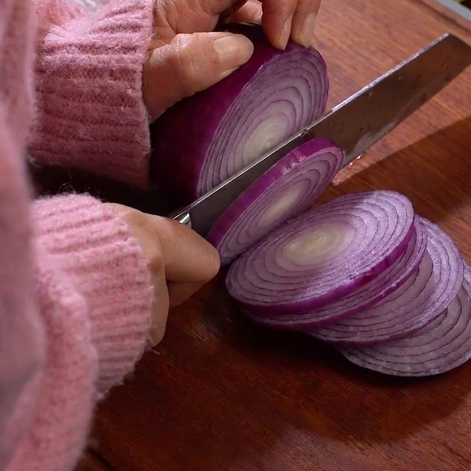 Finas rodajas de raíz de loto sobre una tabla de cortar de madera.
