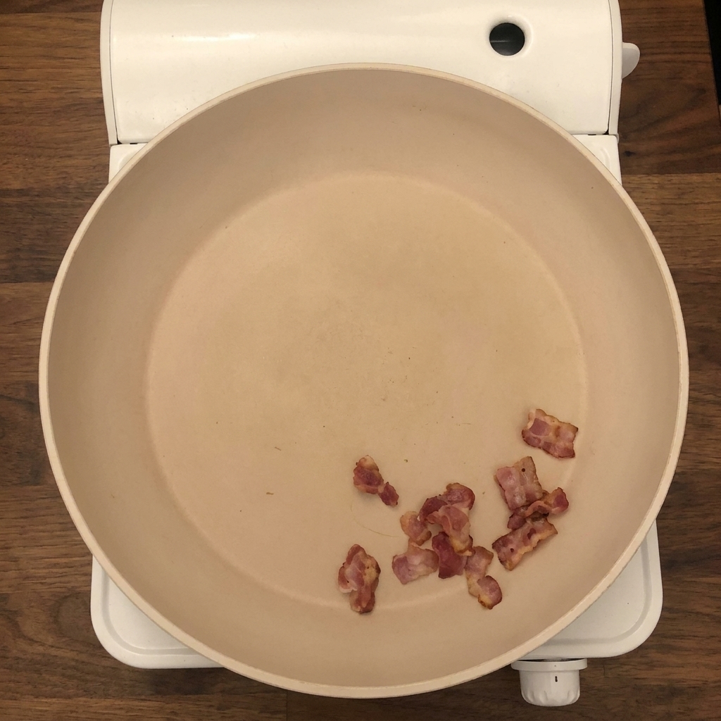 Cebolla fresca y apio picados añadiéndose a la sartén con trozos de tocino crujiente.