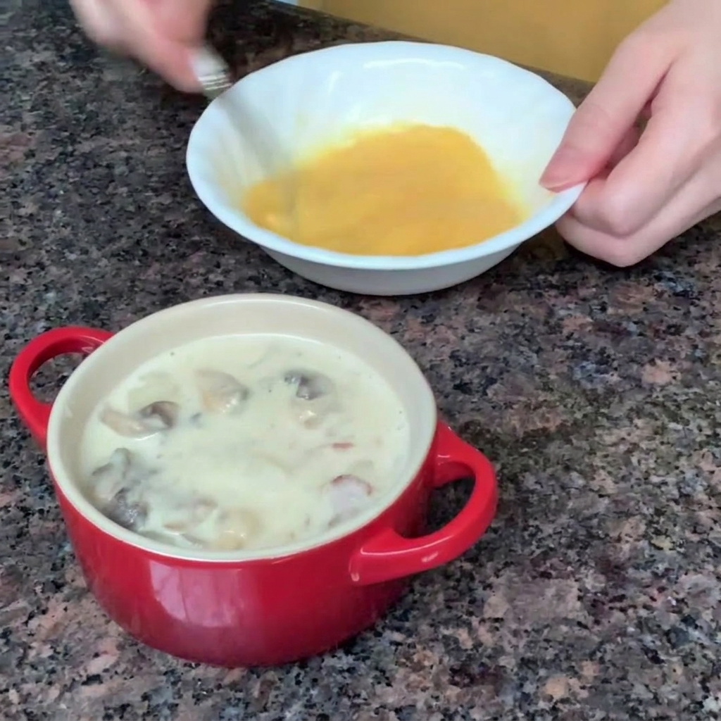 Un huevo siendo batido con un tenedor en un pequeño tazón blanco.