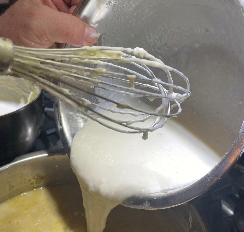 Pimienta blanca siendo espolvoreada sobre una base de sopa de almejas.