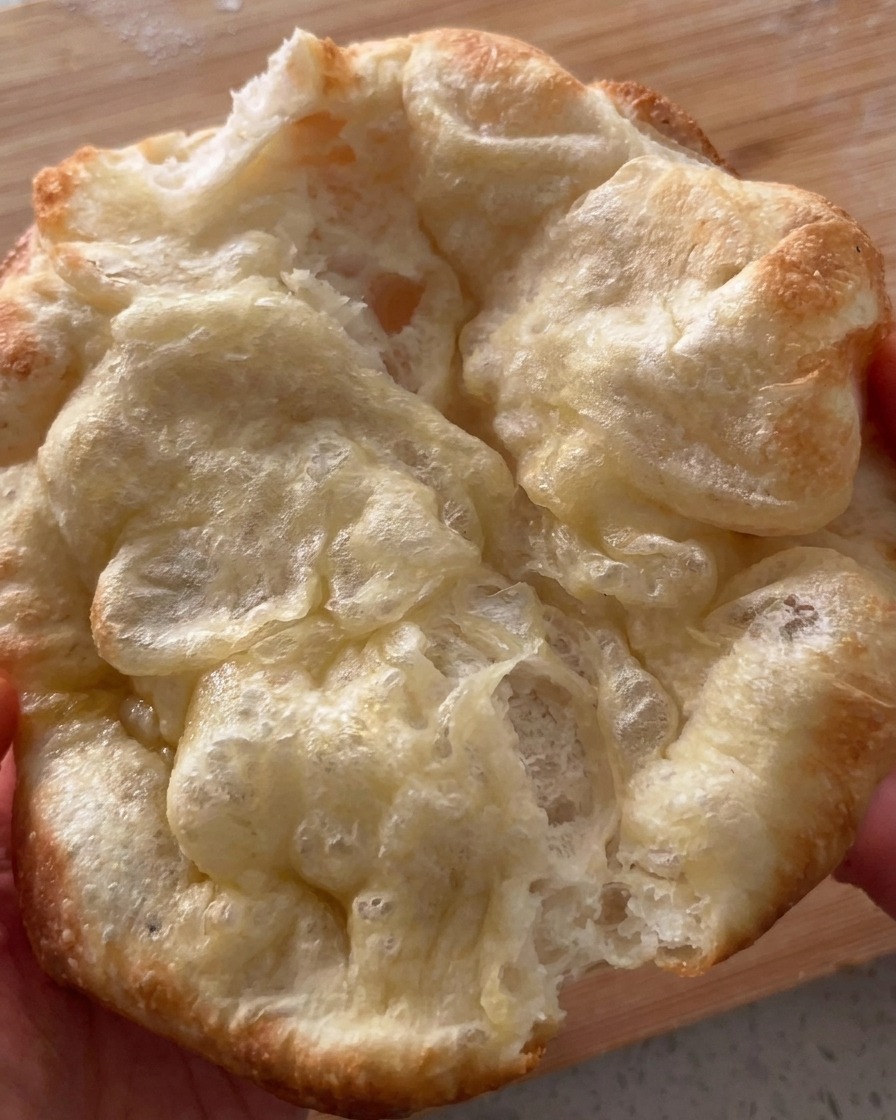 Pan de pizza recién horneado y doblado siendo abierto.