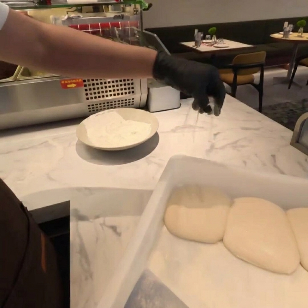 Harina espolvoreada sobre bolas de masa fresca en una encimera de mármol.