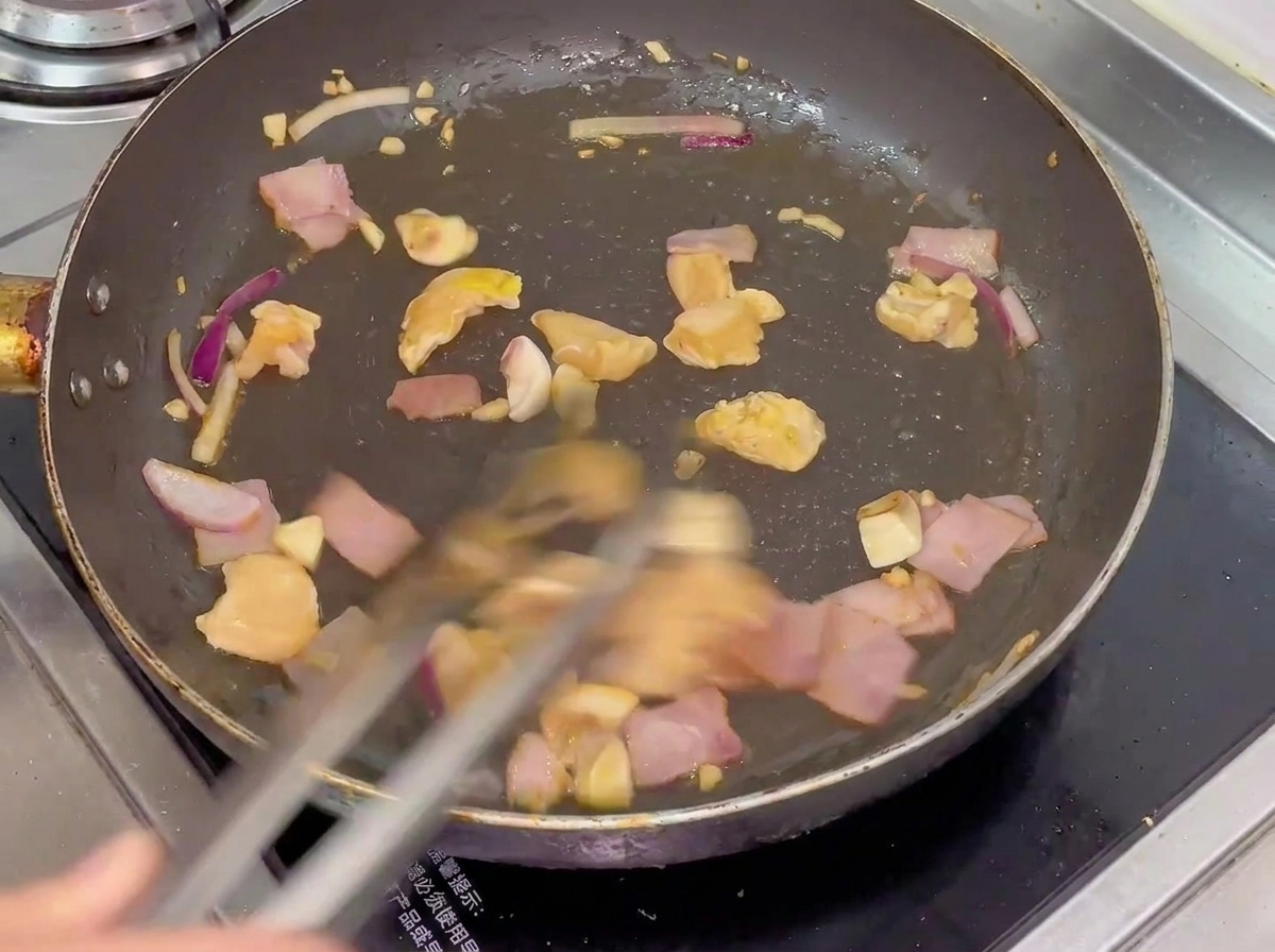Mezcla de pollo, tocino, champiñones y cebolla salteándose en una sartén caliente.