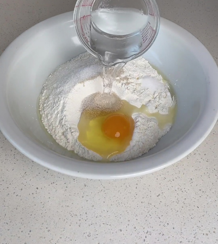 Agua tibia siendo vertida en el bol con la mezcla de ingredientes.