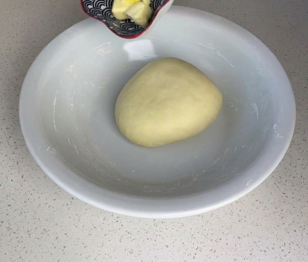 Cubo de mantequilla siendo colocado sobre la bola de masa.