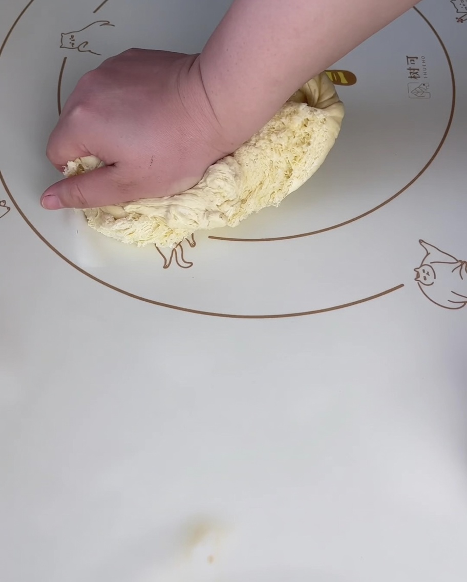 Mano presionando la masa sobre un tapete de silicona para quitar el aire.