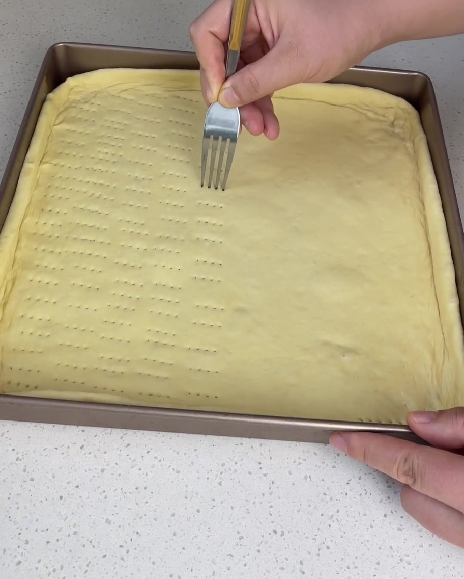 Tenedor pinchando la masa cruda para evitar burbujas.