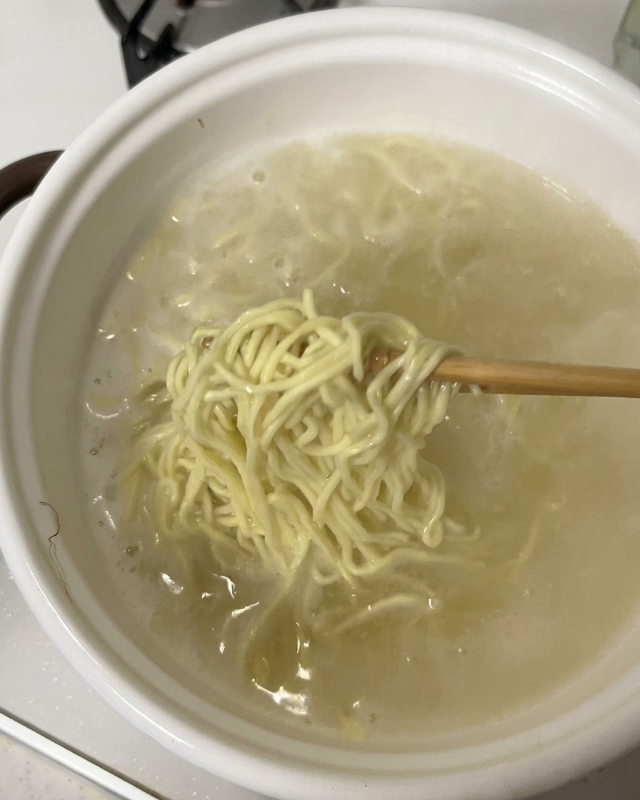 Palillos levantando fideos cocidos de una olla.