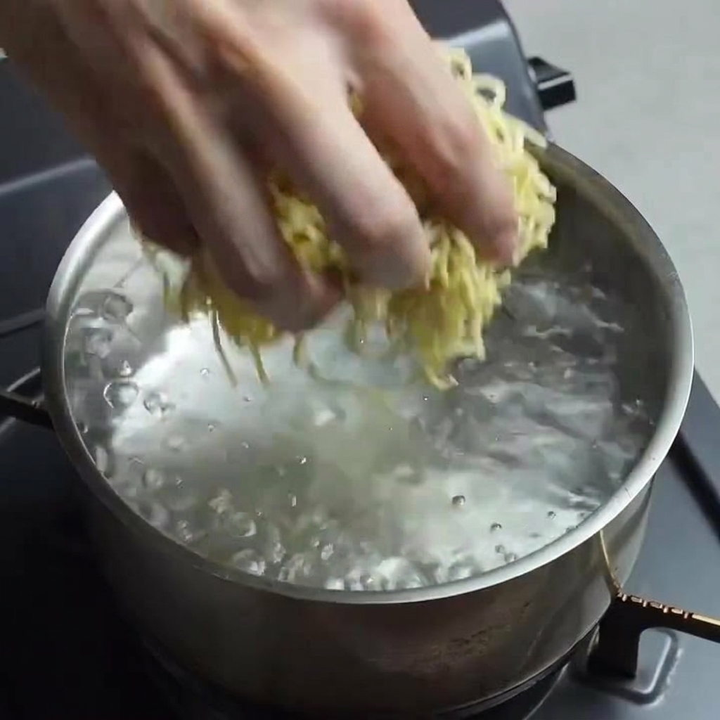 Una mano dejando caer un bloque de fideos frescos de ramen en una olla con agua hirviendo rápidamente.