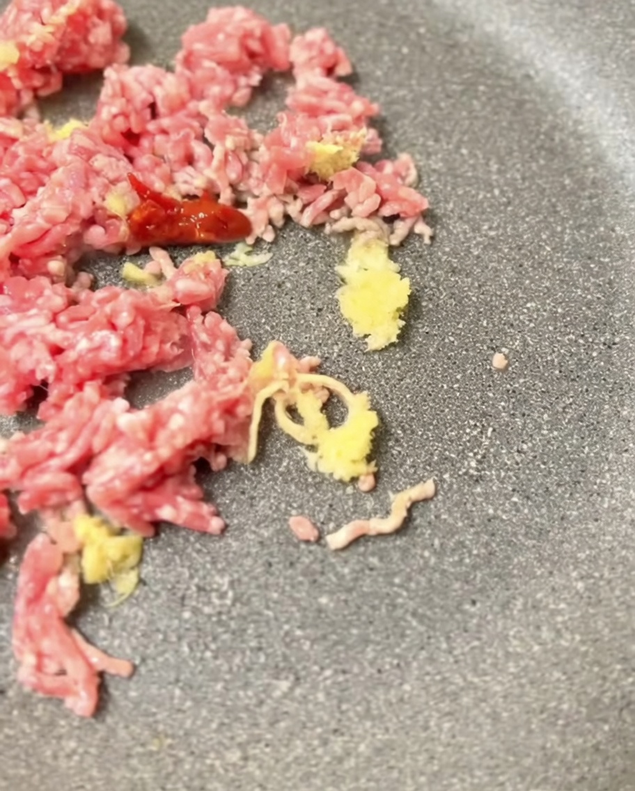 Pasta de miso mezclándose con la carne dorada en la sartén.