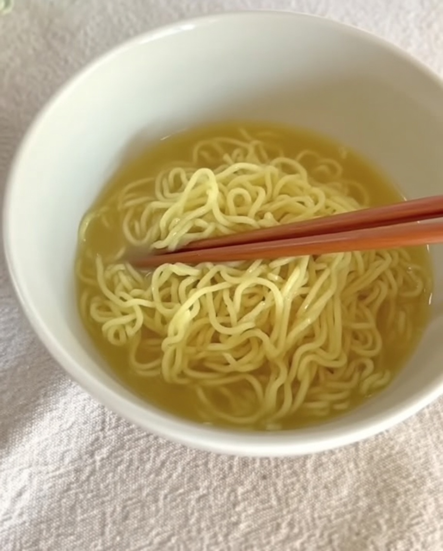 Caldo de Tantanmen cremoso vertiéndose sobre los fideos en un tazón.