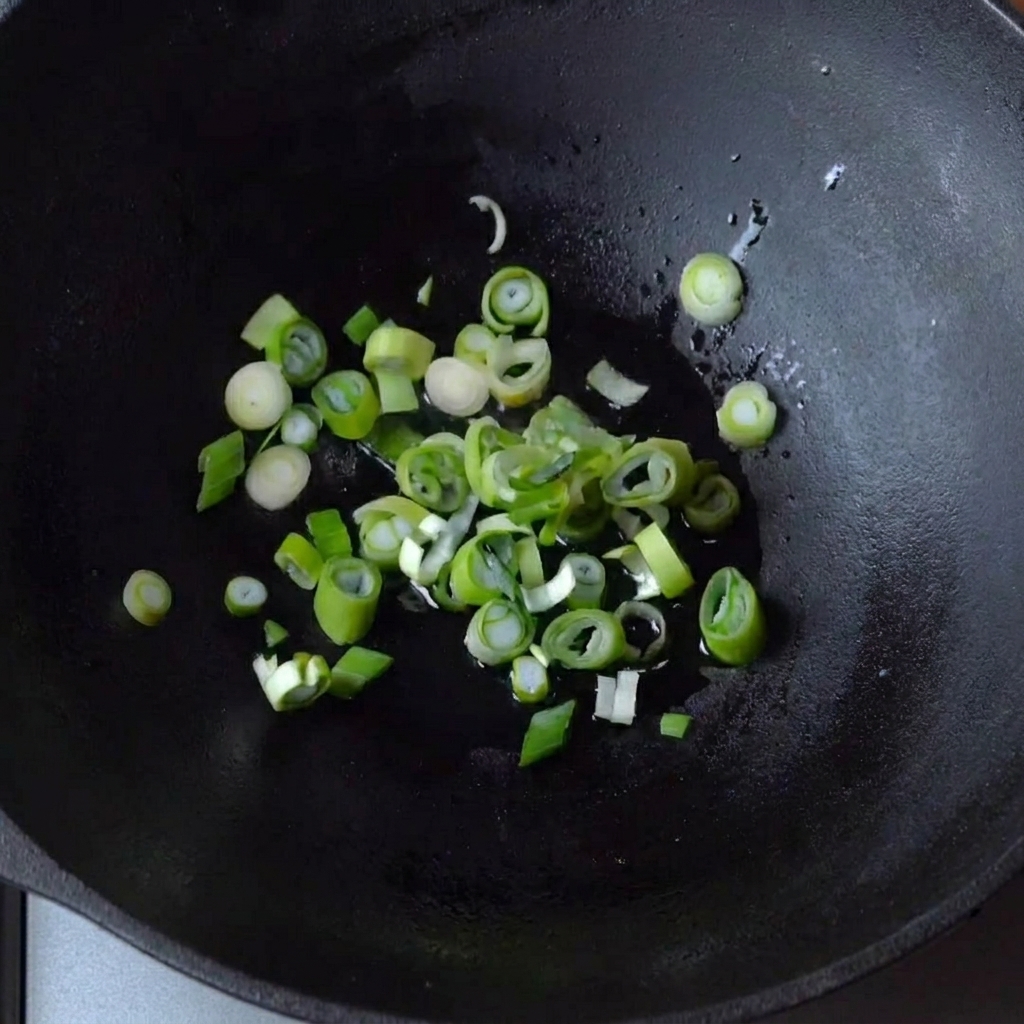 Cebollas verdes salteándose en un wok de hierro fundido.