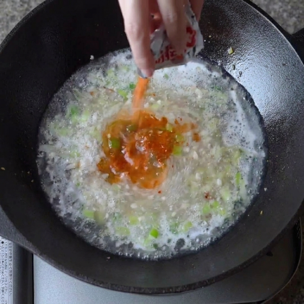 Sazonador de ramen espolvoreado en el caldo hirviendo.