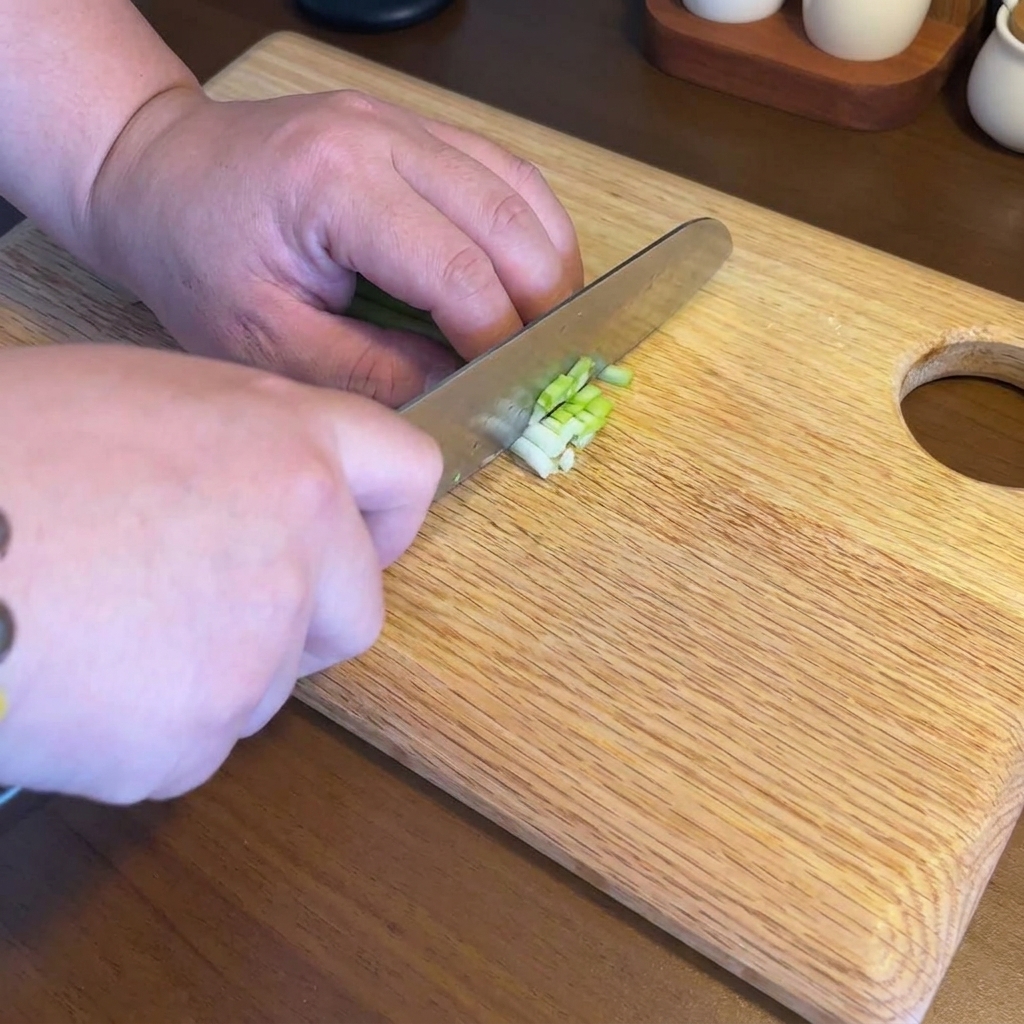 Ajo, jengibre y cebolletas finamente picados y dispuestos sobre una tabla de cortar de madera.