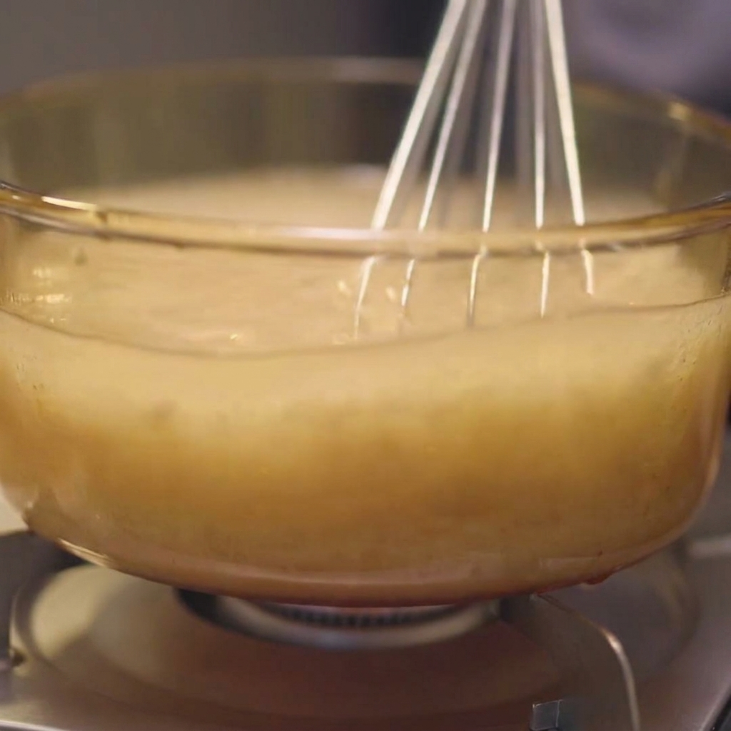 Trozos de kombu siendo sumergidos de nuevo en el caldo de pollo y agua dentro de una olla de cristal.